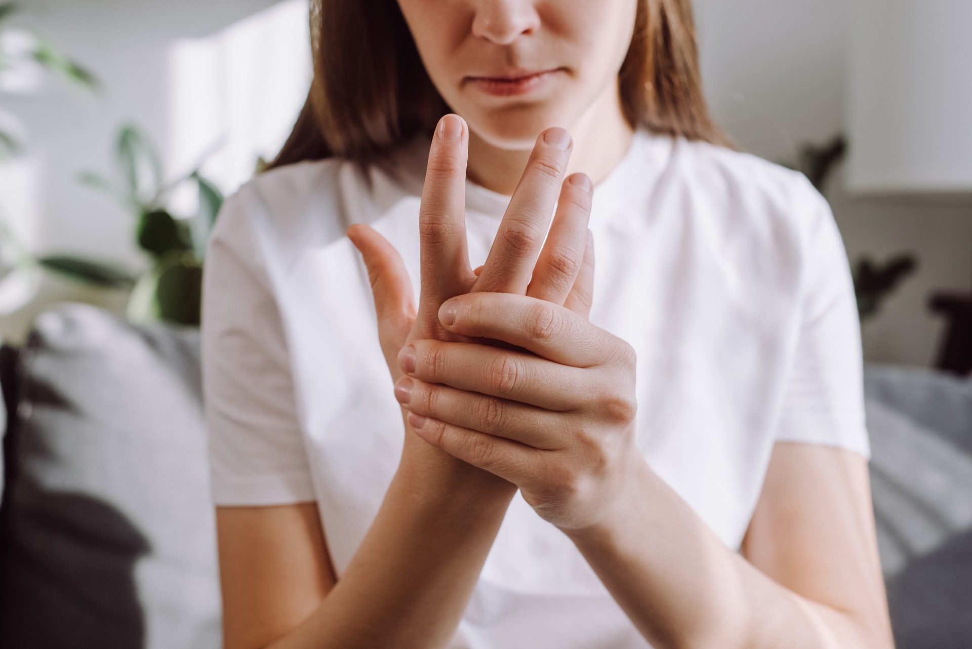 Sad girl massage hand with wrist pain, rheumatoid arthritis concept. Close up of young woman suffer from numbing pain in hand, numbness fingertip, arthritis inflammation, peripheral neuropathies